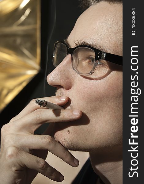 Pensive Young Man In Glasses With A Cigarette