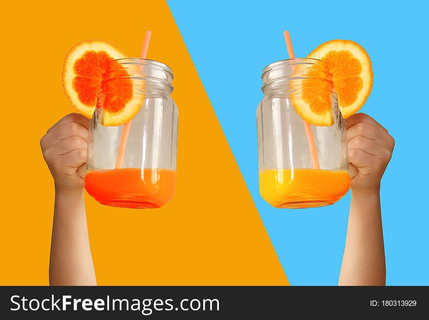Two children are holding a glass jar in their outstretched arms with orange juice from an orange or lemon with a straw, the concept of a healthy diet, vitamins, lifestyle