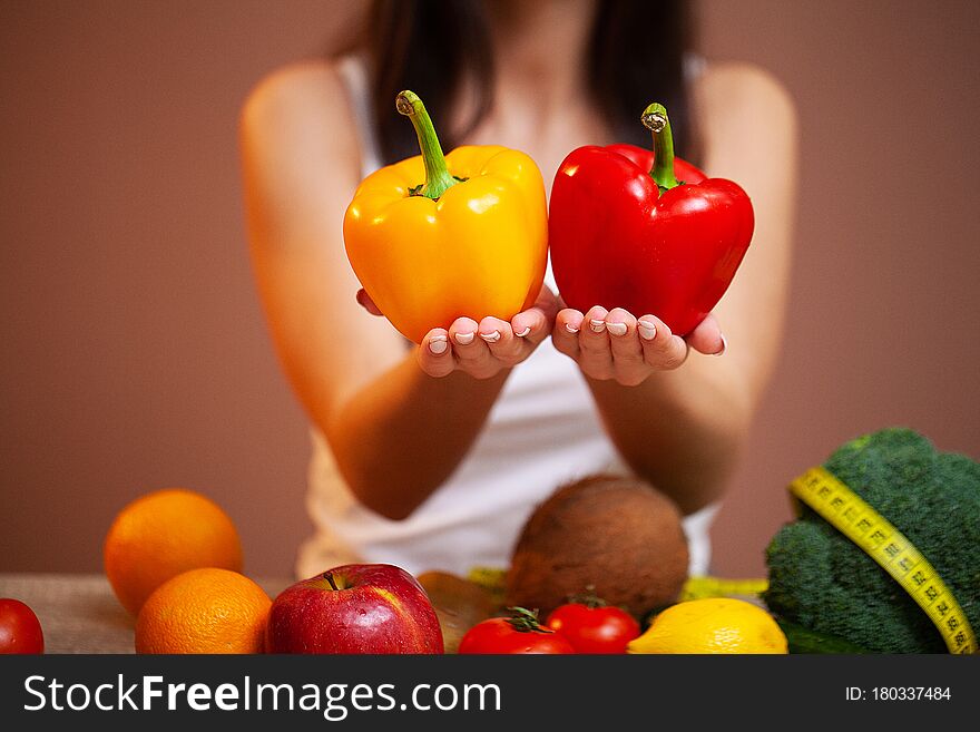 Closeup of woman holding yellow and red peppers in her hands.