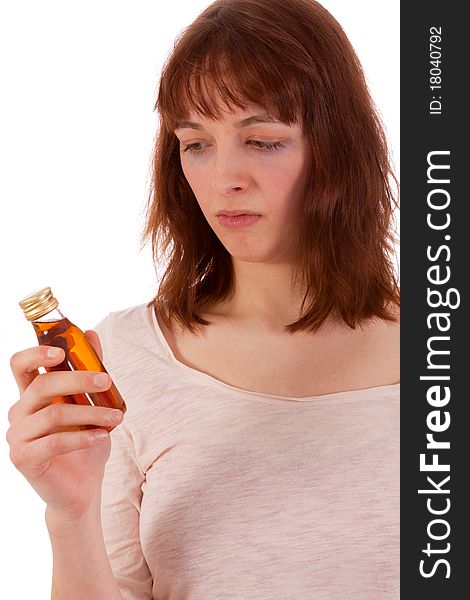 A young woman is critically looking at a bottle of hard liquor. A young woman is critically looking at a bottle of hard liquor