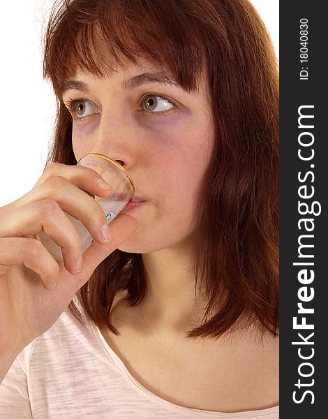 A young woman is drinking white schnapps from a glass. A young woman is drinking white schnapps from a glass