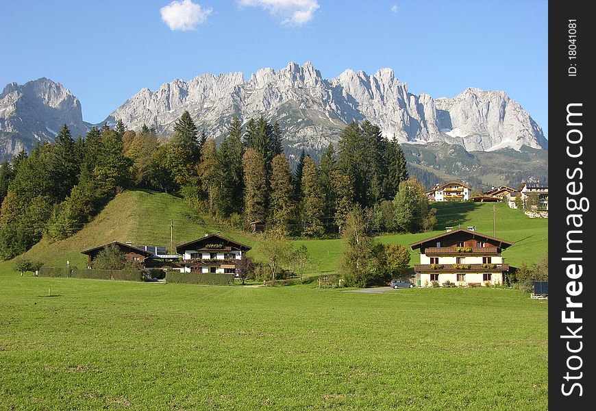 A peaceful alpine land with houses, pinewoods, rock and blue sky. A peaceful alpine land with houses, pinewoods, rock and blue sky.