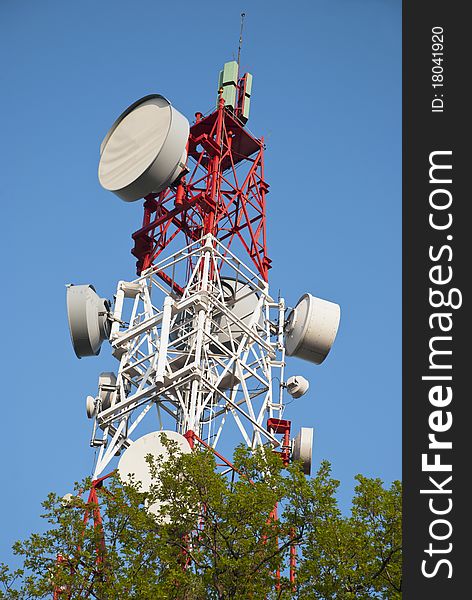 Huge communication antenna tower behind tree. Huge communication antenna tower behind tree