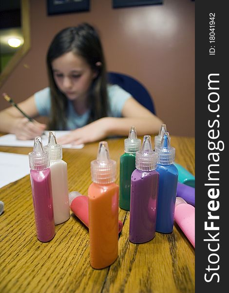 Colorful paint bottles with child drawing in background. Colorful paint bottles with child drawing in background
