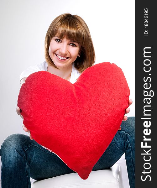 Beautiful young brunette with red heart isolated on white background