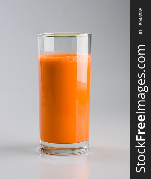 Carroty juice in the glass on gray background