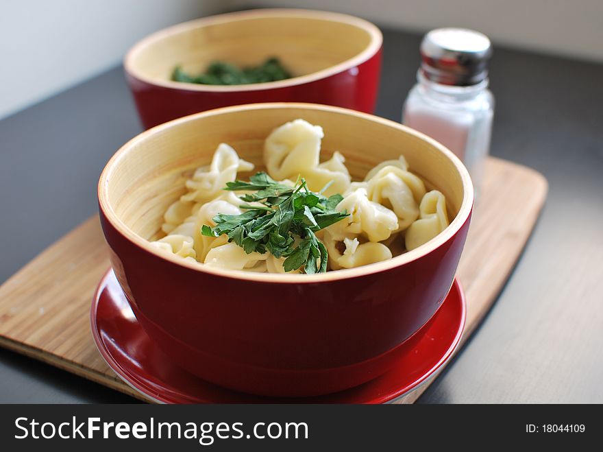 Tortellini with parsley in red bowls