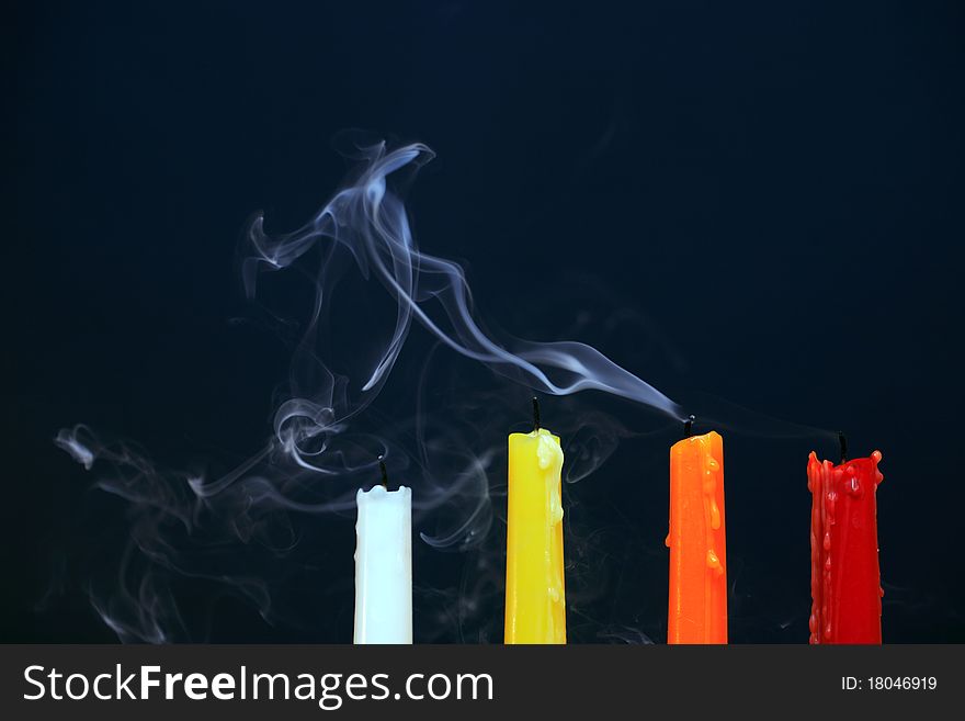 Four color extinguished candles with smoke on black background. Four color extinguished candles with smoke on black background