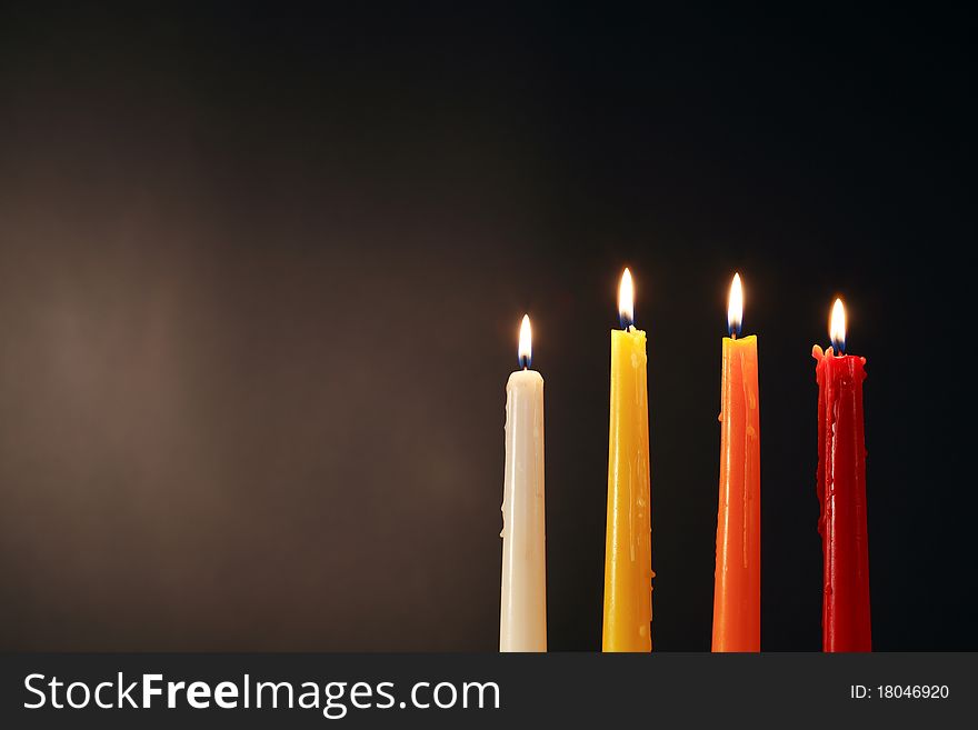 Set of four colored lighting candles on dark background