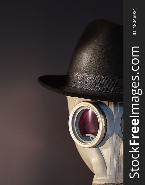 Gas mask with a felt hat closeup on dark background. Gas mask with a felt hat closeup on dark background