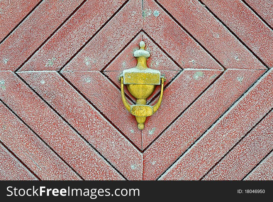 Brass door knocker on a old red frosted door.