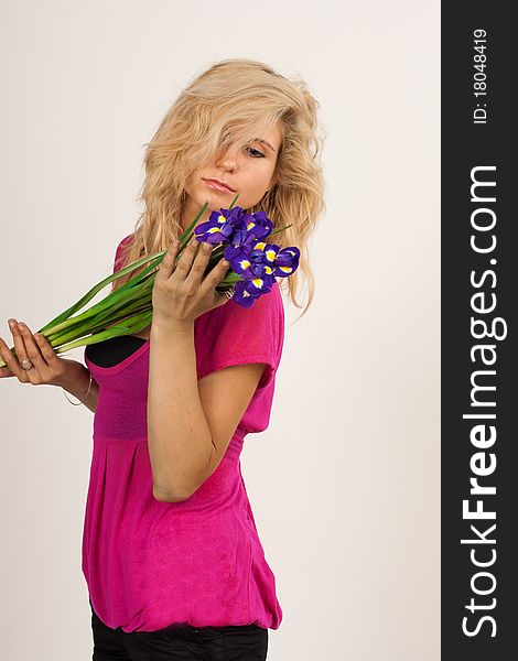 Beautiful girl with blonde hair holding a bouquet of irises. She is in studio isolated on a white background. Beautiful girl with blonde hair holding a bouquet of irises. She is in studio isolated on a white background