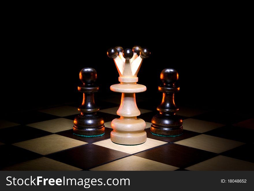 Queen and two pawns on a chess board. A dark art background. Queen and two pawns on a chess board. A dark art background.