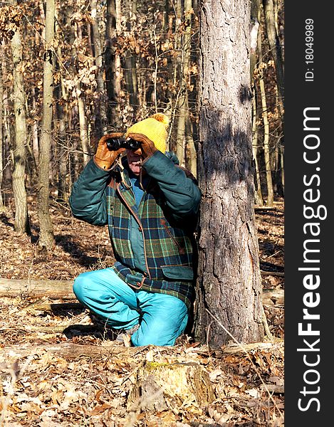 Senior man is watching the wildlife with binoculars in winter forest. Senior man is watching the wildlife with binoculars in winter forest