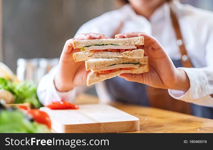 Closeup image of a female chef cooking and showing a whole wheat sandwich in kitchen