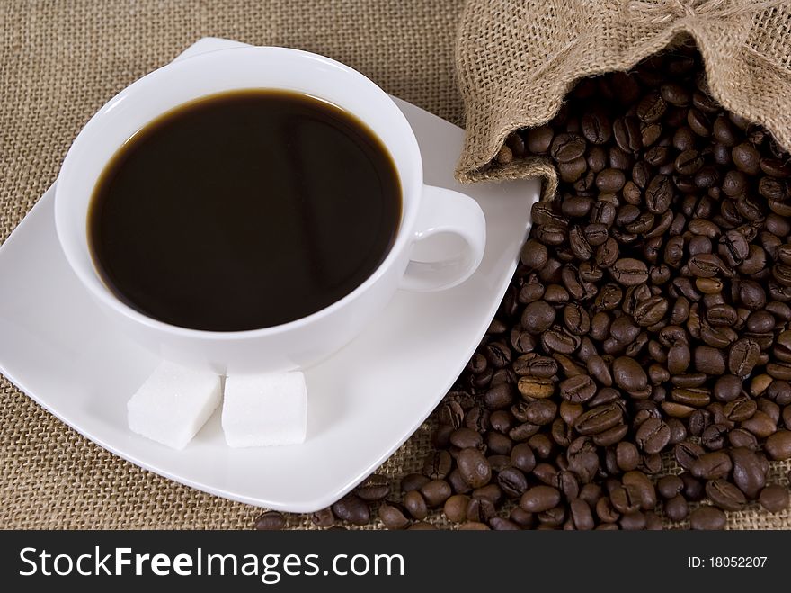 Cup with coffee and spilled grains of coffee