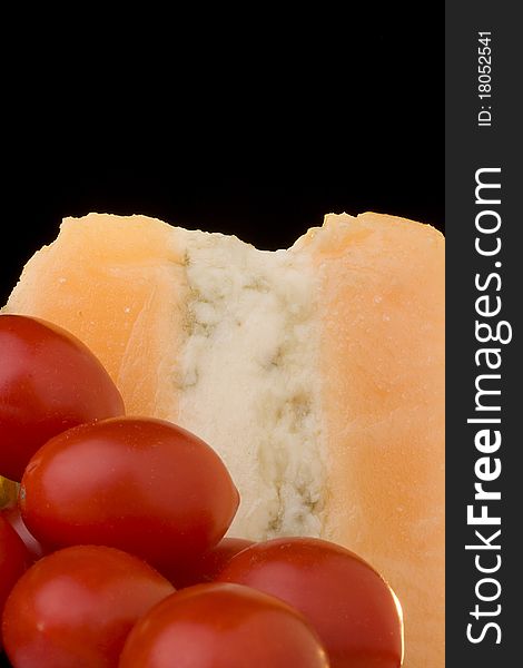 Gloucester cheese with Cheese blue slice on a black background with tomato. Gloucester cheese with Cheese blue slice on a black background with tomato.