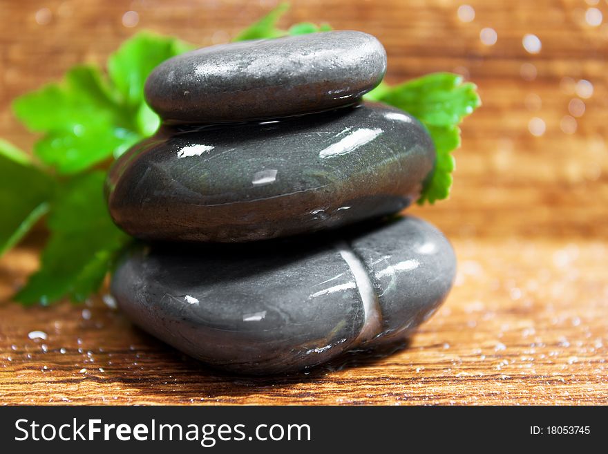 Three wet spa stones on wood for a natural beauty.