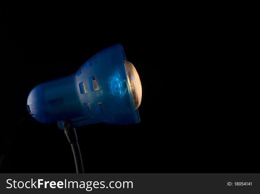 The desktop dark blue lamp burns on a black background