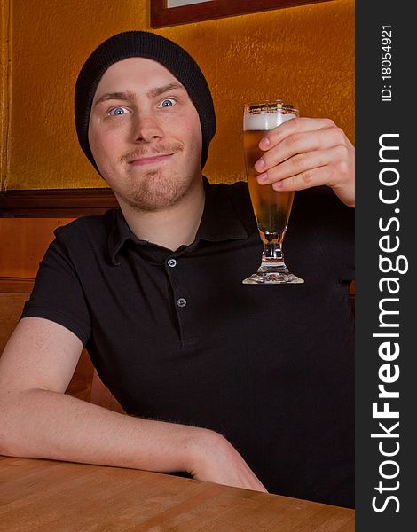 A young man is sitting in pub and drinking a beer. A young man is sitting in pub and drinking a beer