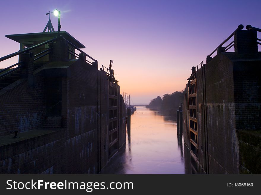 A sluice at a beautiful tranquil morning with warm light on the lock gates. A sluice at a beautiful tranquil morning with warm light on the lock gates.