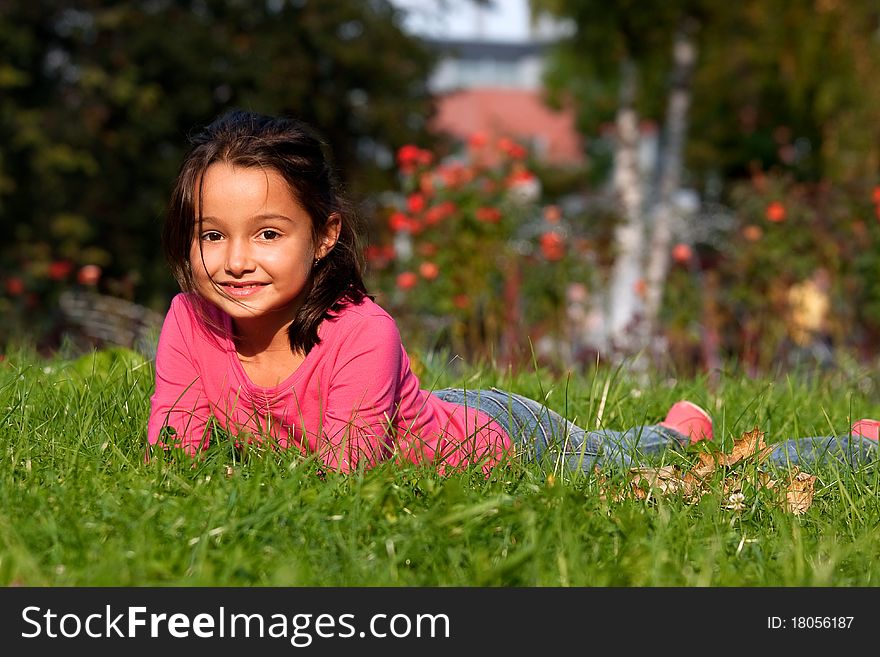 Happy little girl laying on the grass in the park. Happy little girl laying on the grass in the park