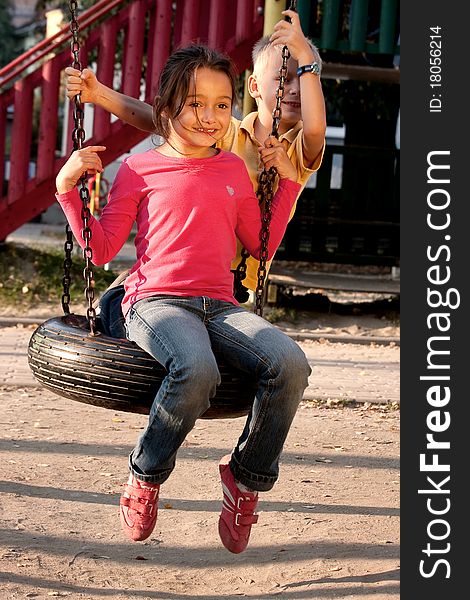 Boy and girl on swing playground outdoors