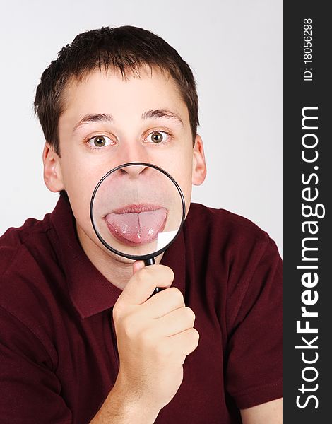 Young man holding magnifier and showing tongue through it