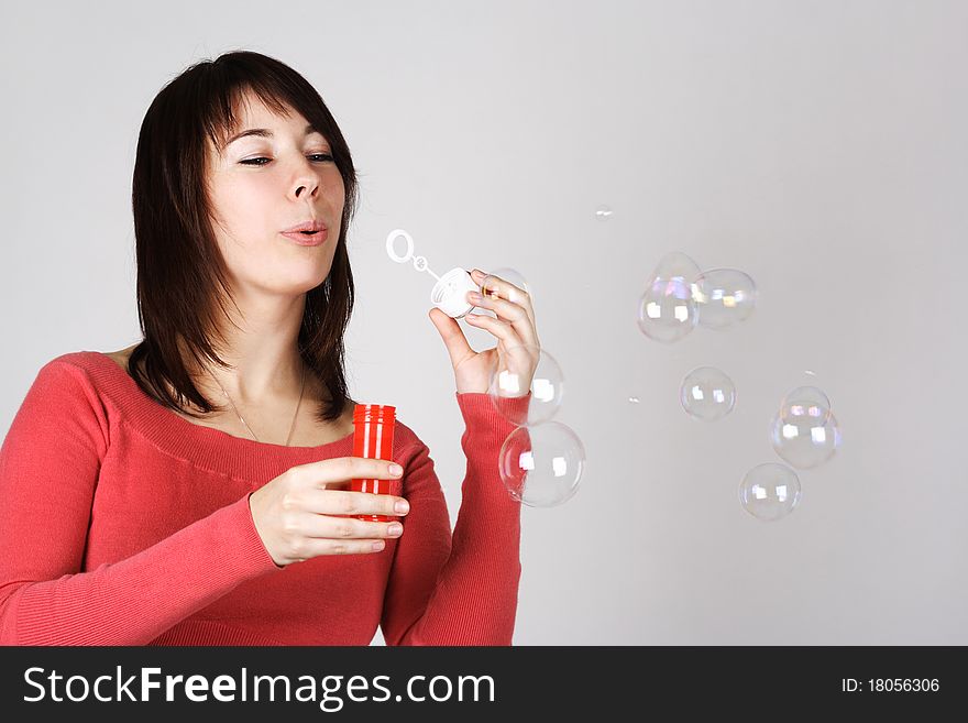 Woman in red shirt blowing out soap bubbles