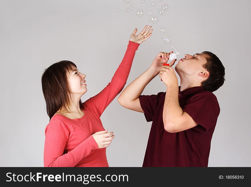 Man blowing out soap bubbles, girl catching it