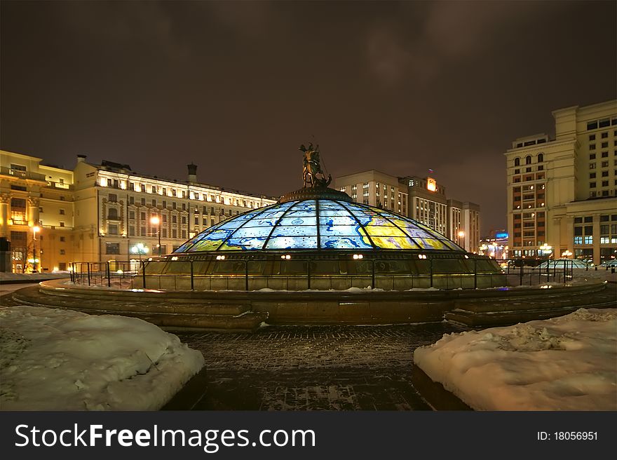 Glass cupola crowned by a statue of Saint George, holy patron of Moscow, with the Manege looming in the background , winter's night, Moscow, Russia
