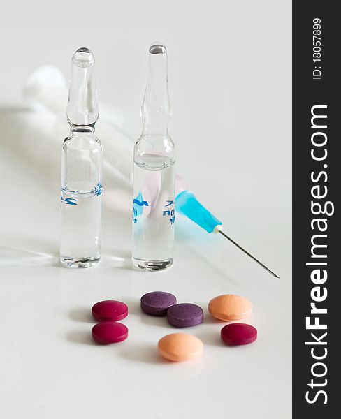 Multicolored vitamin pills with two ampoules and syringe. Multicolored vitamin pills with two ampoules and syringe.