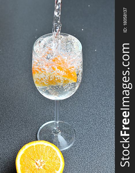 Pouring Water Into Glass With Orange