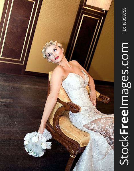 Bride blond with a bouquet sits on a chair