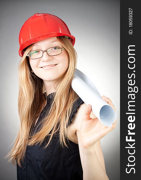 Young woman in helmet with blueprint, with grey background. Young woman in helmet with blueprint, with grey background