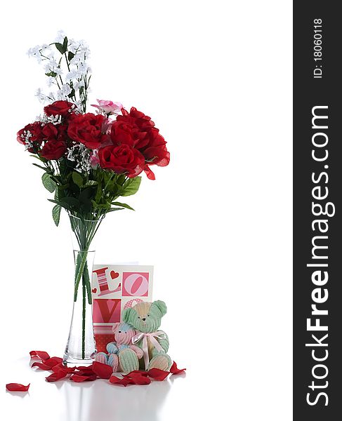 A studio front view of a pair of teddy bears sitting in front of a valentine greeting with a vase of flowers and scattered rose pedals casting a frontal shadow on a white background. A studio front view of a pair of teddy bears sitting in front of a valentine greeting with a vase of flowers and scattered rose pedals casting a frontal shadow on a white background.