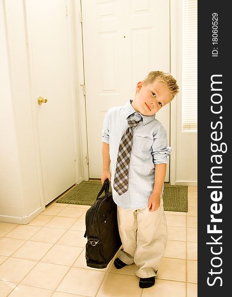 A cute young boy is dressed as a businessman, and stands by the door, carrying a briefcase. A cute young boy is dressed as a businessman, and stands by the door, carrying a briefcase
