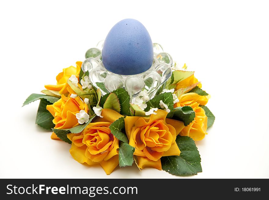 Colored egg in the glass bowl and with bunch of flowers