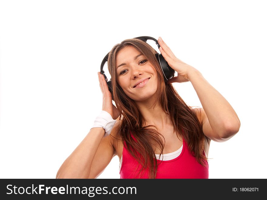 Attractive fitness brunette woman listening and enjoyingmusic in headphones, smiling, laughing and looking in camera isolated on a white background