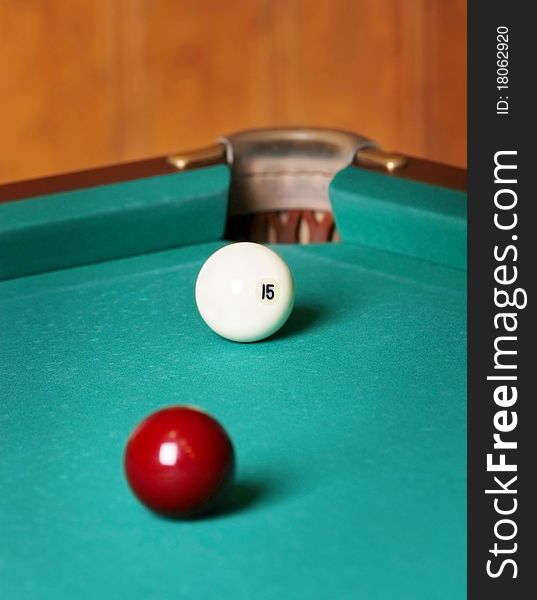 Two billiard spheres stand opposite to a billiard pocket