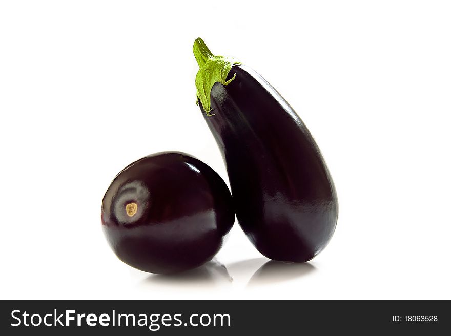 Black eggplants photographed on white background.