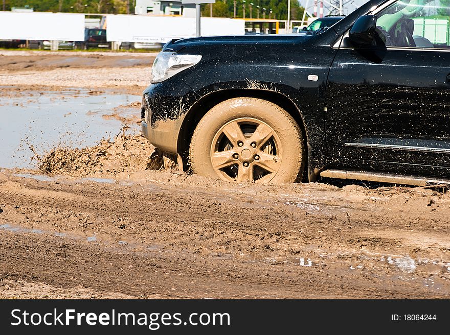 A car sprays mud as it zips around a corner in a dirt road rally. A car sprays mud as it zips around a corner in a dirt road rally