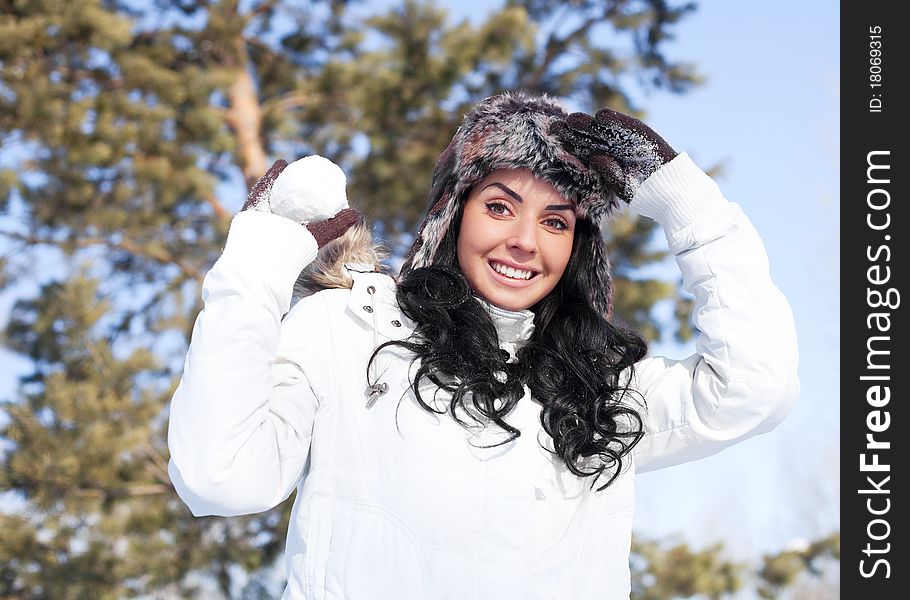 Pretty young brunette woman playing snowballs in winter outdoor. Pretty young brunette woman playing snowballs in winter outdoor