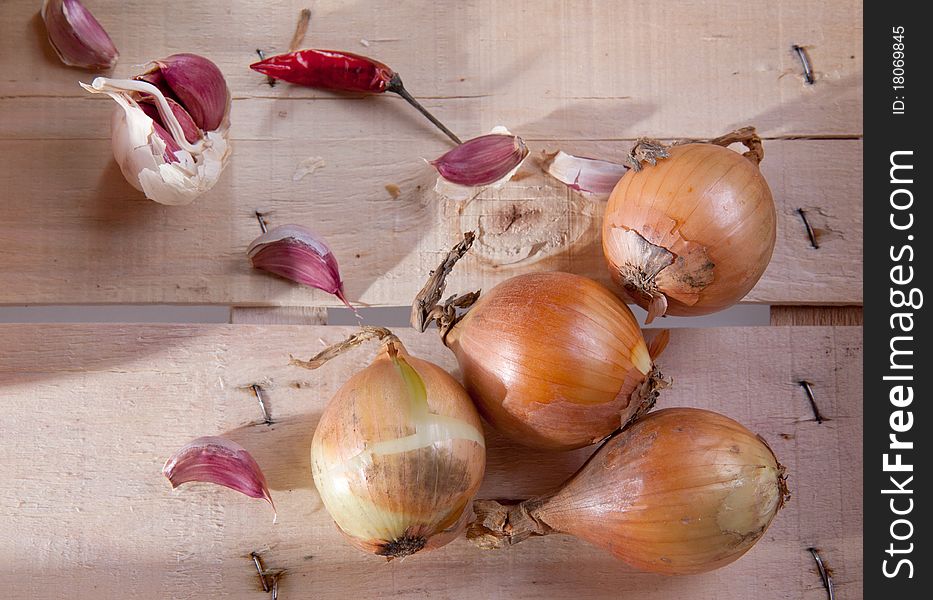 Onion, garlic and pepper on a wooden desk in sun shine