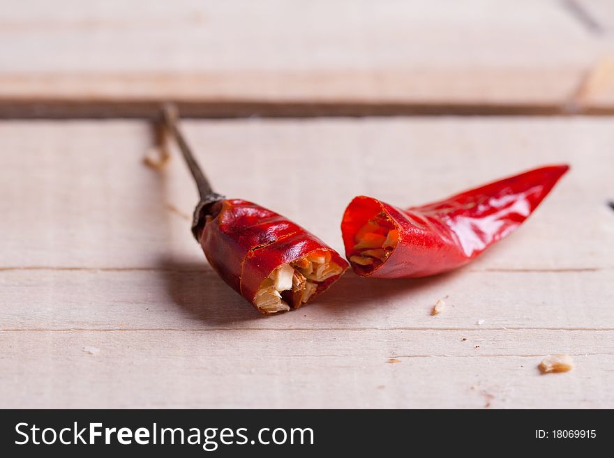 Breaking red hot chili pepper on the wooden desk