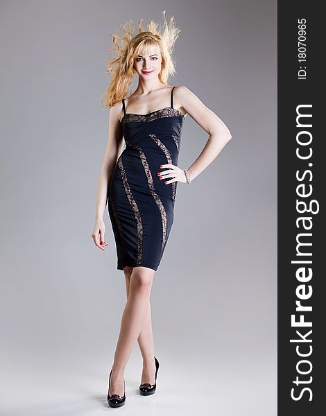 Young beautiful high blonde in a black dress and shoes on a high heel