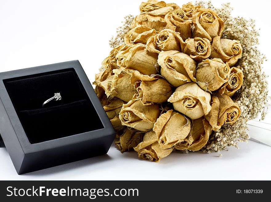 Dried roses bouquet and engagement ring on white