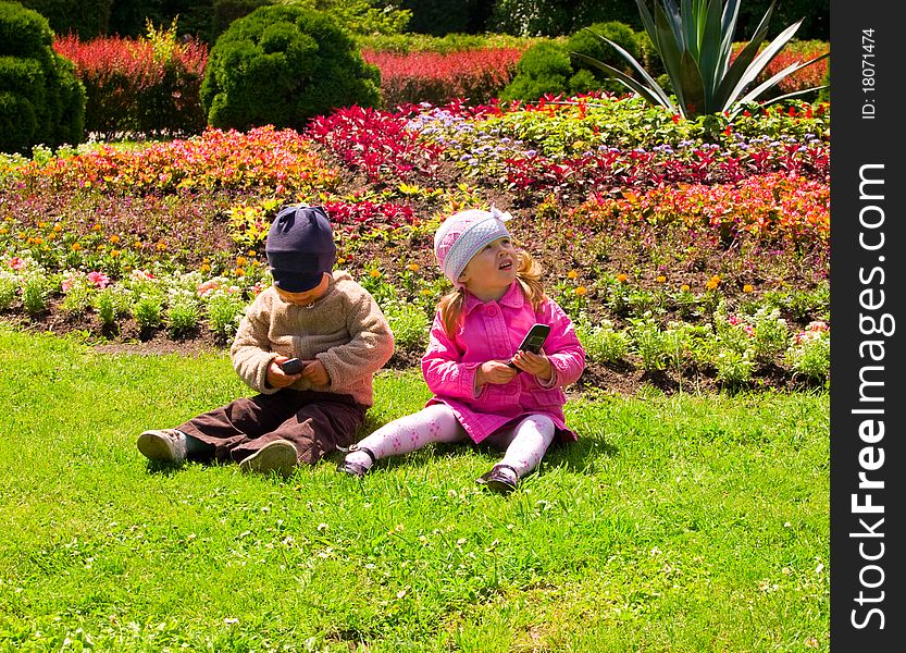 Boy and girl playing in the park with mobile phones