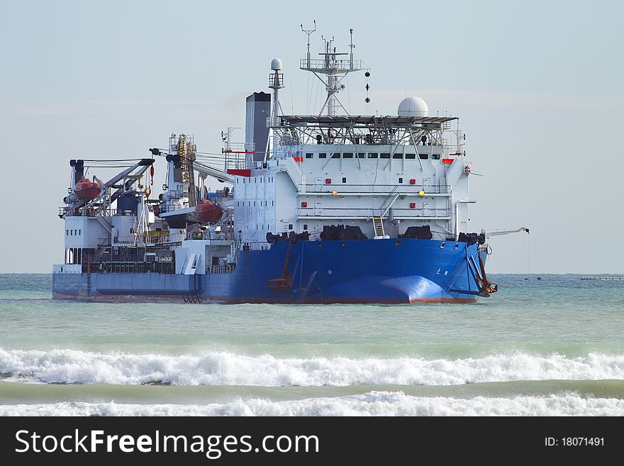 Big vessel distributing power cable near the beach. Big vessel distributing power cable near the beach