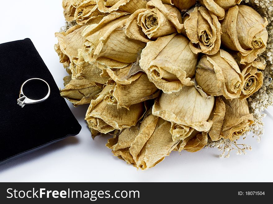 Dried roses bouquet and engagement ring on white